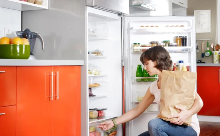 donna che mette la spesa dentro al frigo
