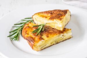 due fette di frittata di patate su un piatto con accanto del rosmarino