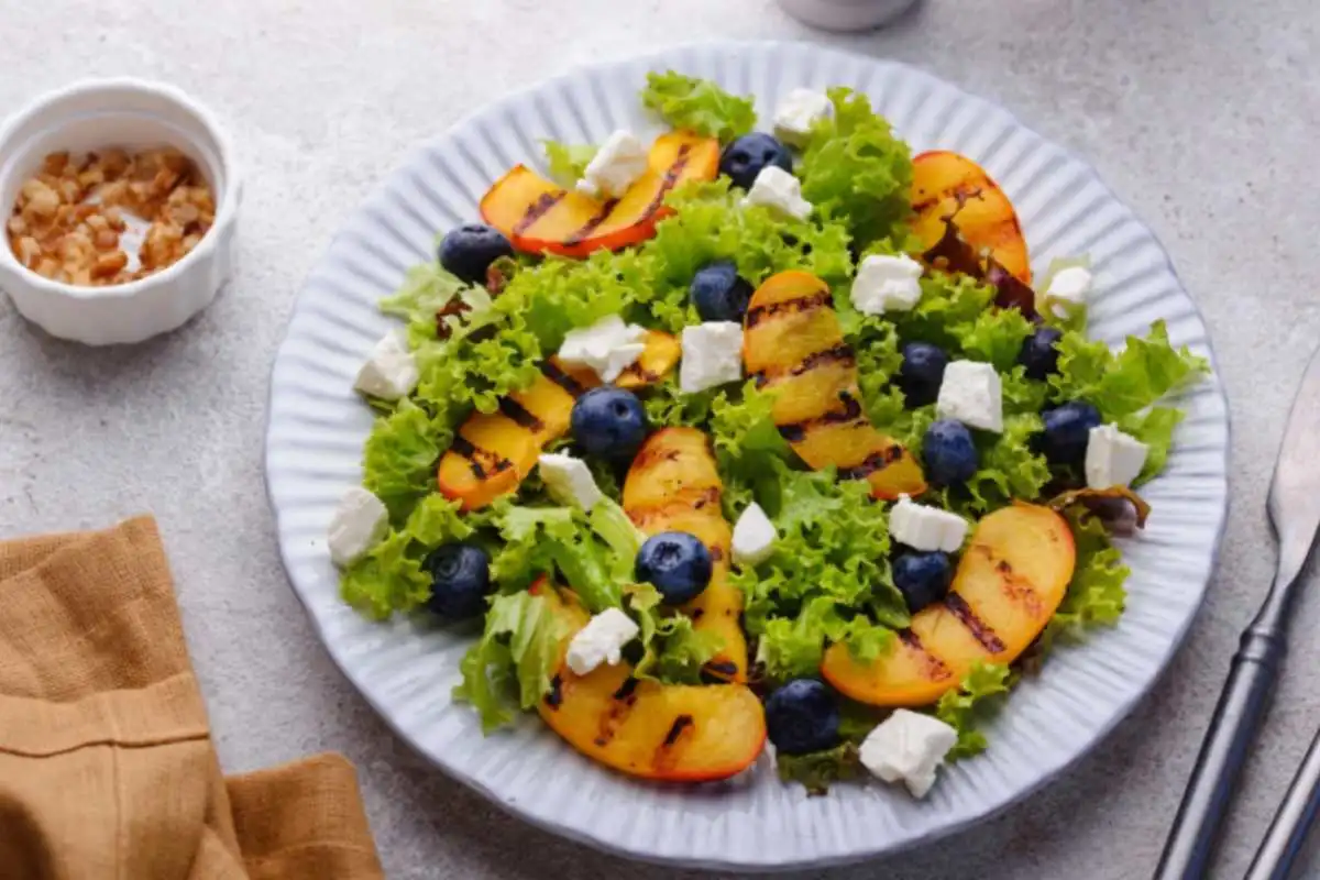 insalatona con pesche tofu e mirtilli dentro ad un piatto
