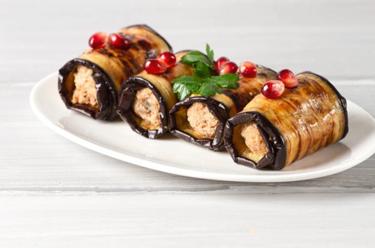 involtini di melanzane su un piatto con sopra dei chicchi di melograno