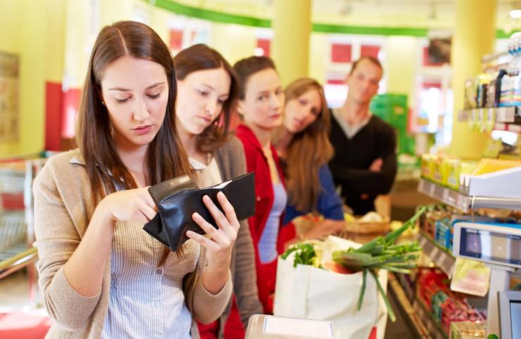 persone alla cassa del supermercato e donna che guarda dentro al suo portafoglio