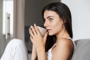 donna seduta sul divano con in mano una tazzina di caffè