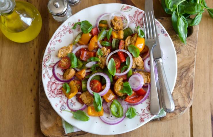 insalata panzanella dentro ad un piatto con accanto forchetta e coltello
