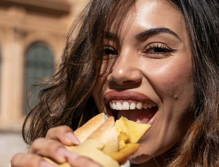 una ragazza mangia un panino