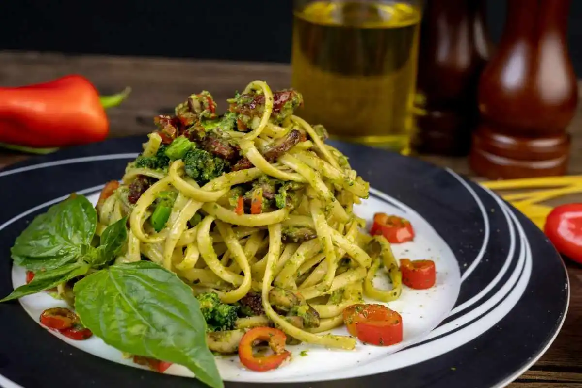 Piatto di spaghetti con melanzane, basilico, pomodori e pesto
