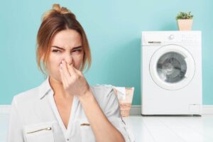 lavatrice e ragazza che sente cattivo odore