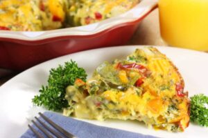 fetta di torta alle verdure su un piatto con accanto una forchetta