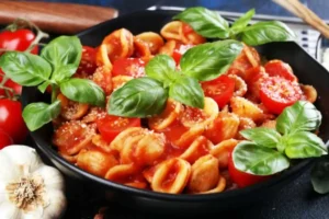 piatto di orecchiette al pomodoro con foglie di basilico fresco