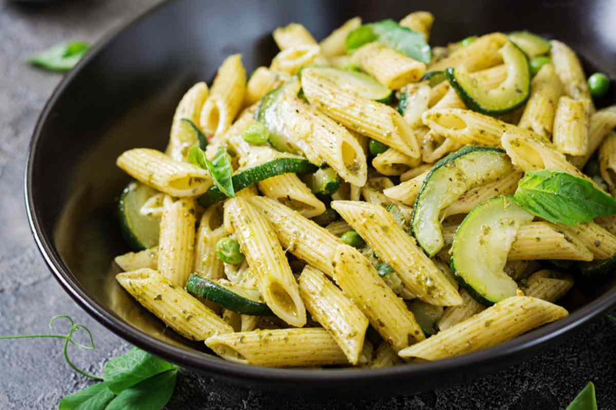 pasta con zucchine pisellini e foglie di menta dentro ad un piatto nero