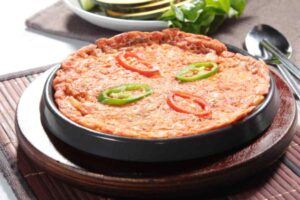frittata di riso al pomodoro con sopra dei peperoni tagliati a rondelle