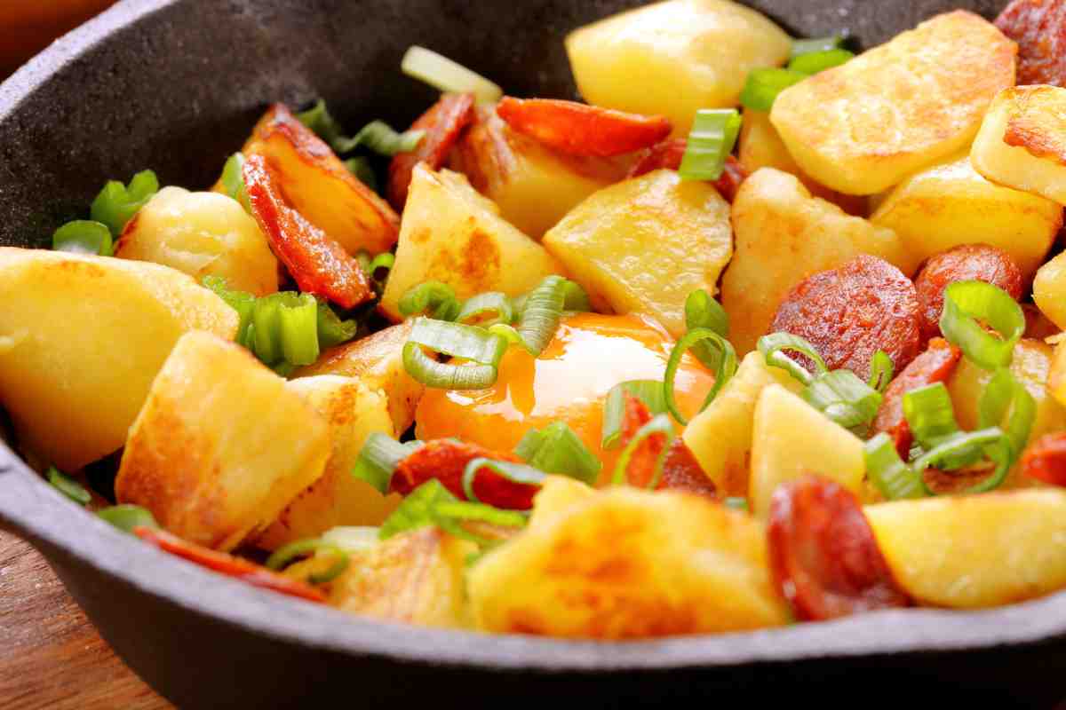 Piatto con salsicce, patate sparse e pomodorini