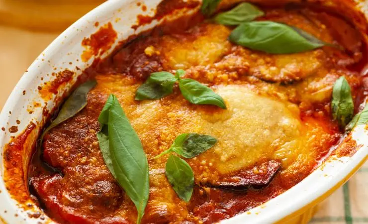 Pasticcio di melanzane nel vassoio con foglie di basilico