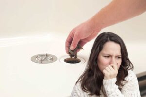 uno scarico intasato e una ragazza che si tiene il naso
