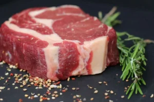 fetta di carne cruda e accanto un rametto di rosmarino