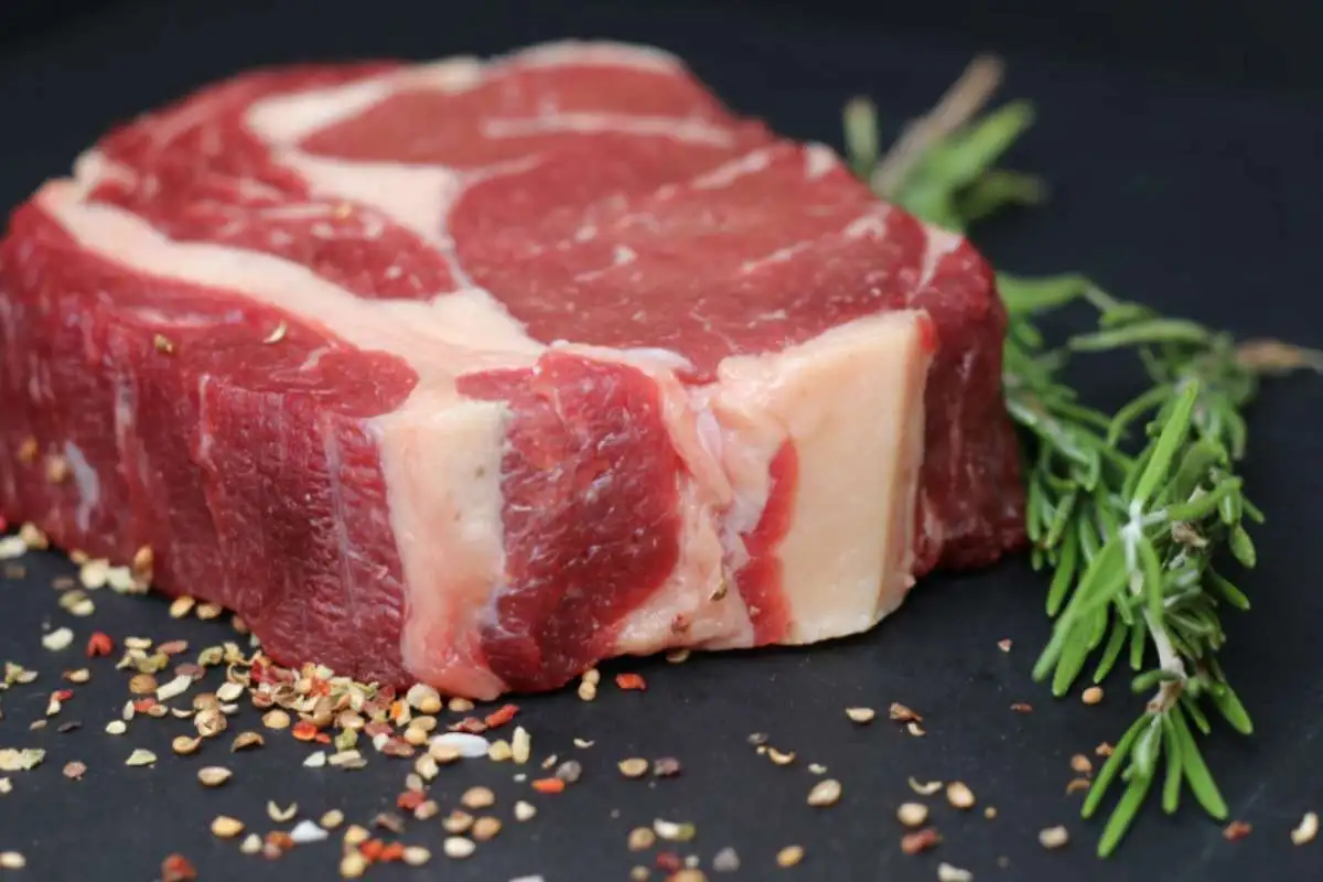 fetta di carne cruda e accanto un rametto di rosmarino