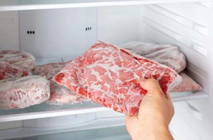 persona che tira fuori della carne dal freezer