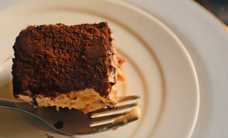Fetta di dolce con cacao in polvere e forchetta nel piatto