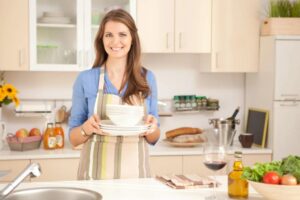 donna in cucina con il grembiule e dei piatti in mano