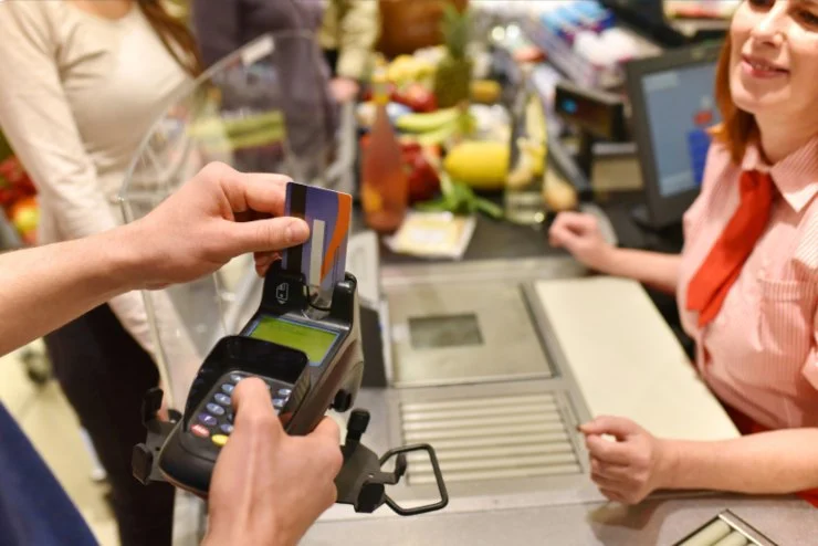 persona alla cassa del supermercato che inserisce il bancomat nel pos per pagare