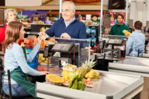 anziano che paga alla cassa del supermercato con dei contanti
