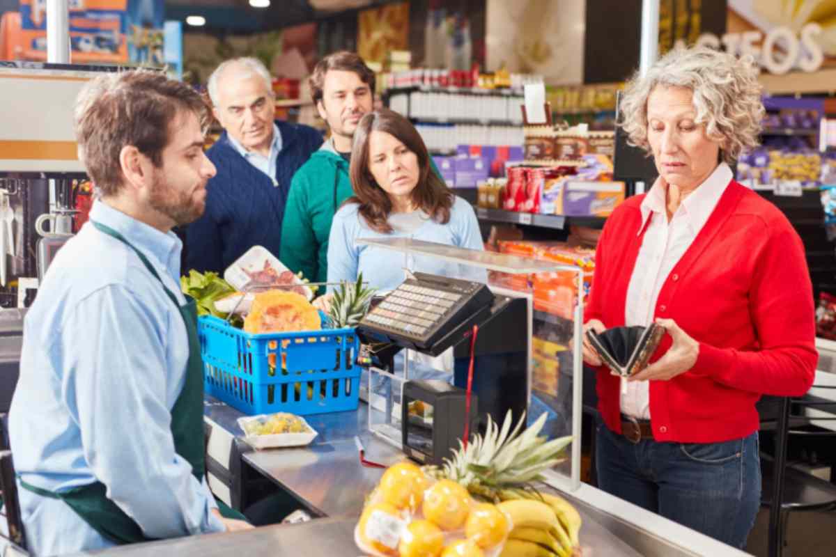 donna che guarda dentro al portafoglio mentre è alla cassa del supermercato