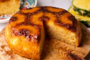 torta all'ananas senza una fetta sopra ad un tagliere di legno