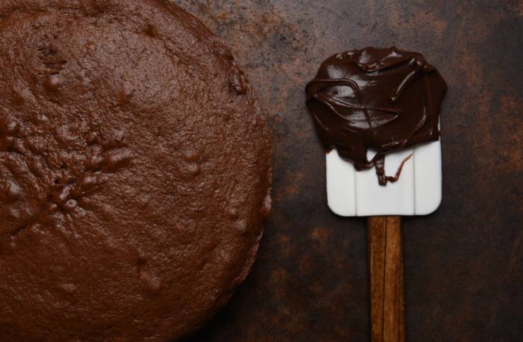 torta al cioccolato e accanto cioccolato fuso sopra ad una spatola da cucina
