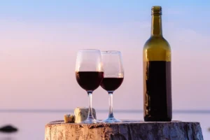 calici e bottiglia di vino rosso al mare