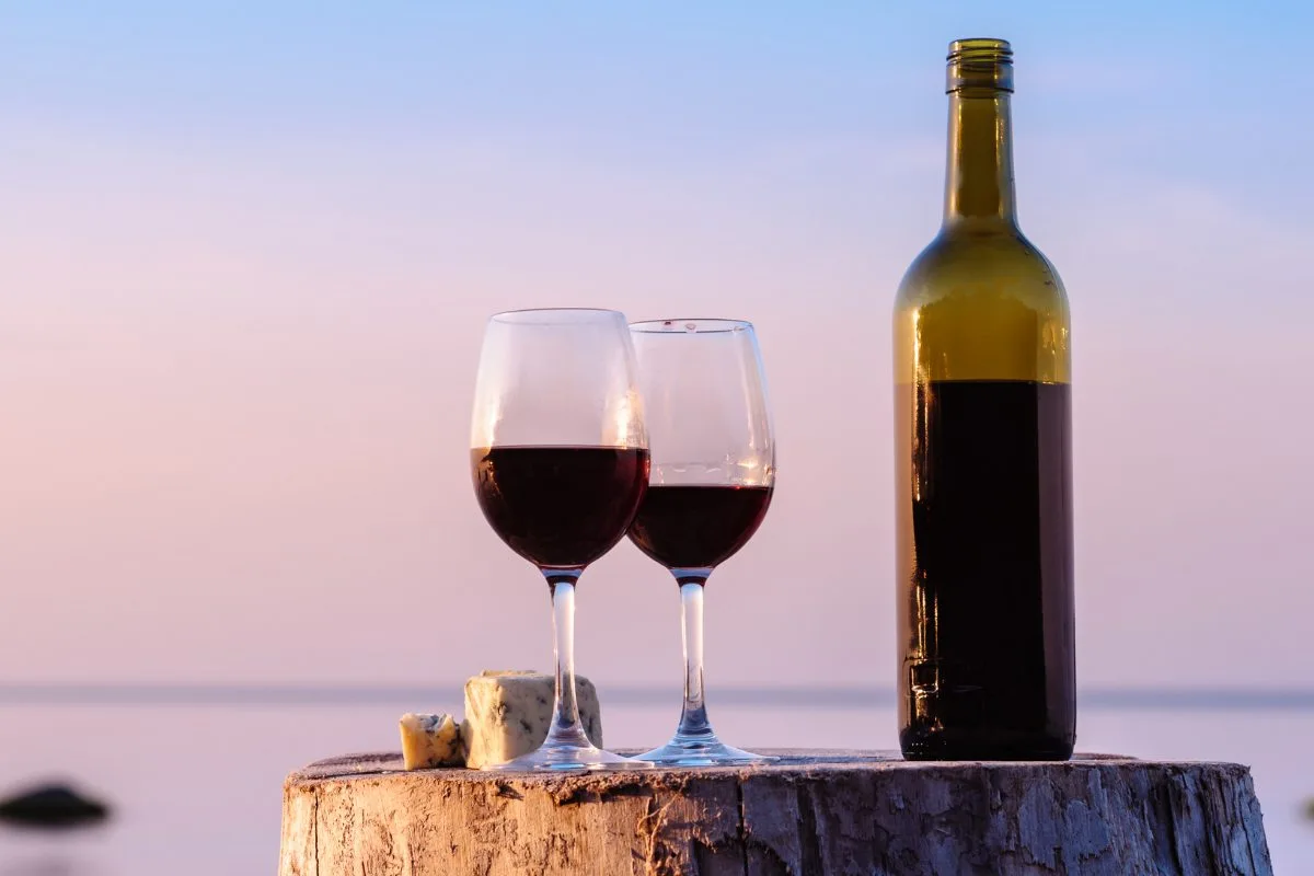 calici e bottiglia di vino rosso al mare