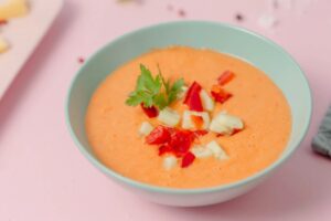 zuppa di pomodoro dentro ad un piatto con sopra delle verdurine e del prezzemolo