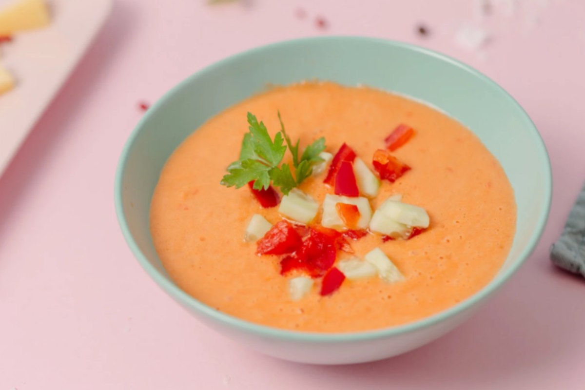 zuppa di pomodoro dentro ad un piatto con sopra delle verdurine e del prezzemolo