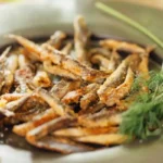 Alici fritte in un piatto con limone e rosmarino