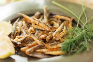 Alici fritte in un piatto con limone e rosmarino