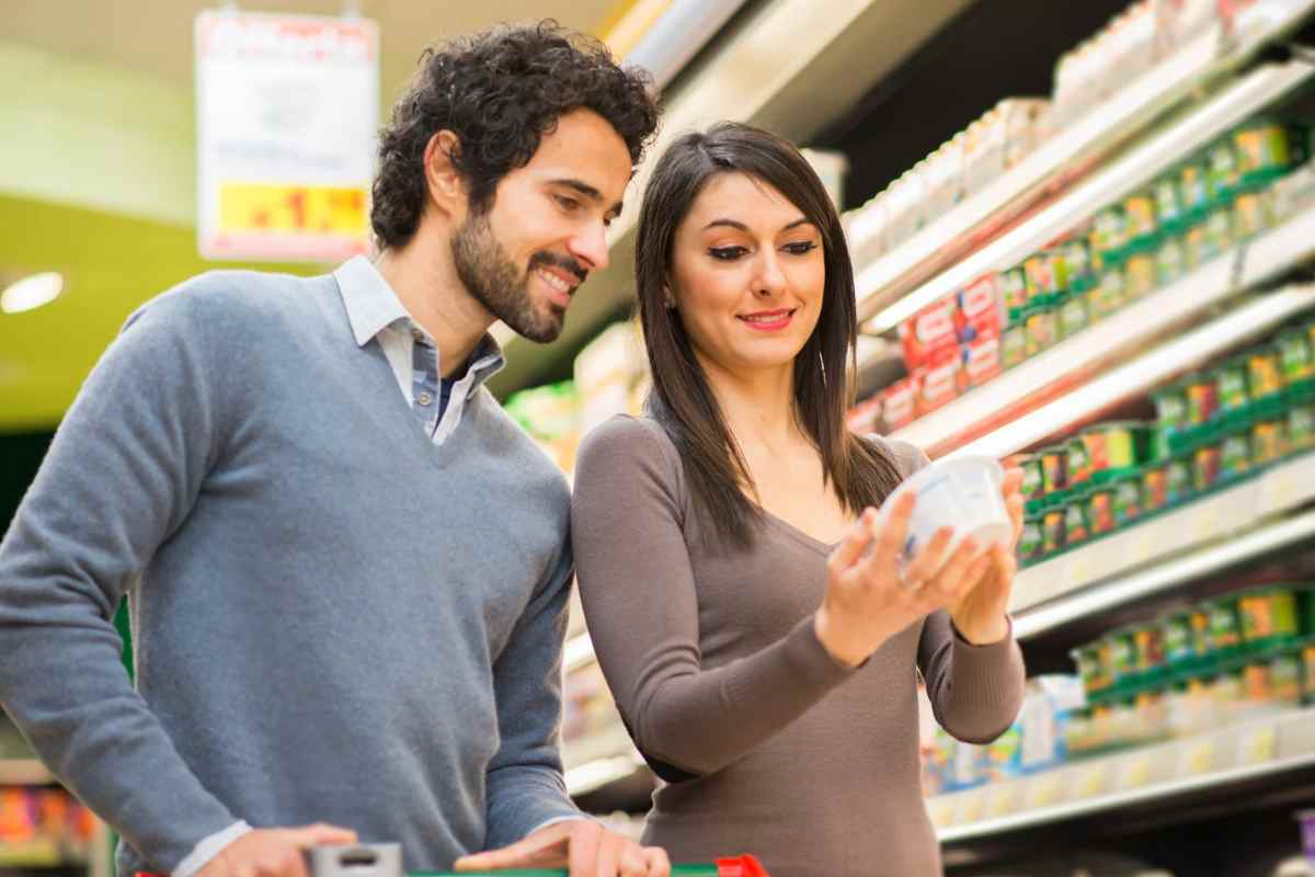 Un uomo e una donna sorridenti che osservano una confezione in un supermercato