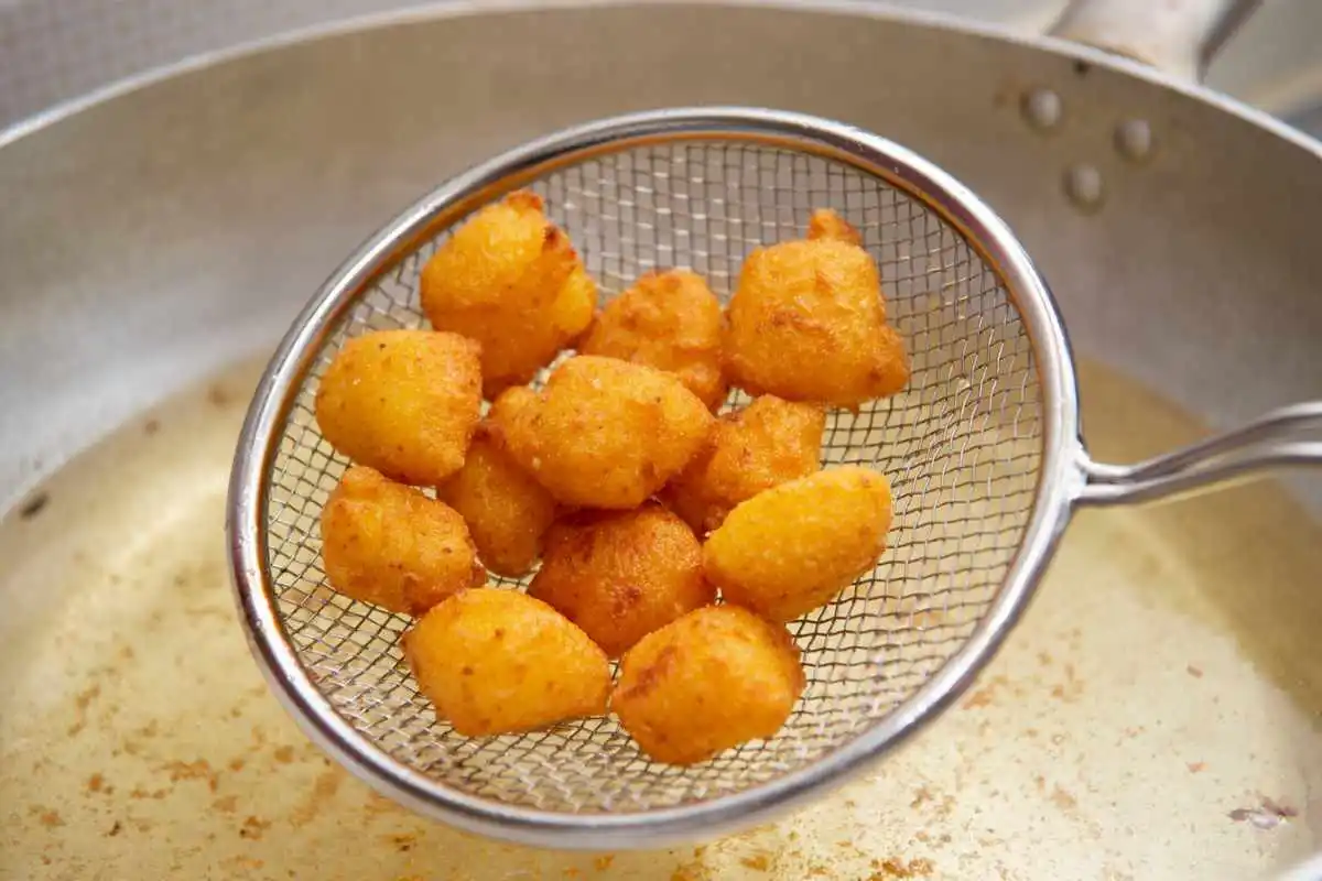 Bocconcini di crema fritta in una schiumarola