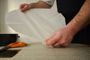 Uomo che stende carta da forno con le mani