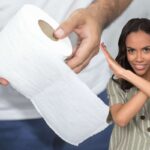 persona srotola carta igienica e ragazza fa la x con le braccia
