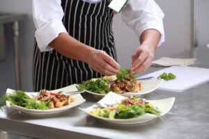 Chef che impiatta pietanze a base di insalata