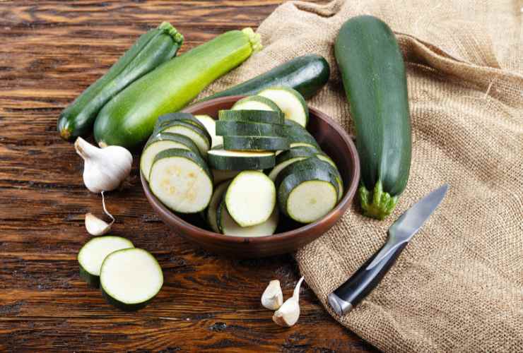 zucchine tagliate in una ciotola e intere sul tavolo