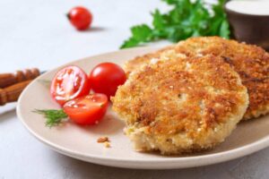 cotolette in un piatto con accanto dei pomodorini
