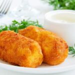 due crocchette su un piatto con accanto una ciotolina con della salsa