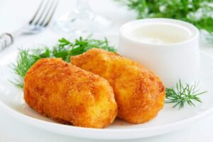 due crocchette su un piatto con accanto una ciotolina con della salsa