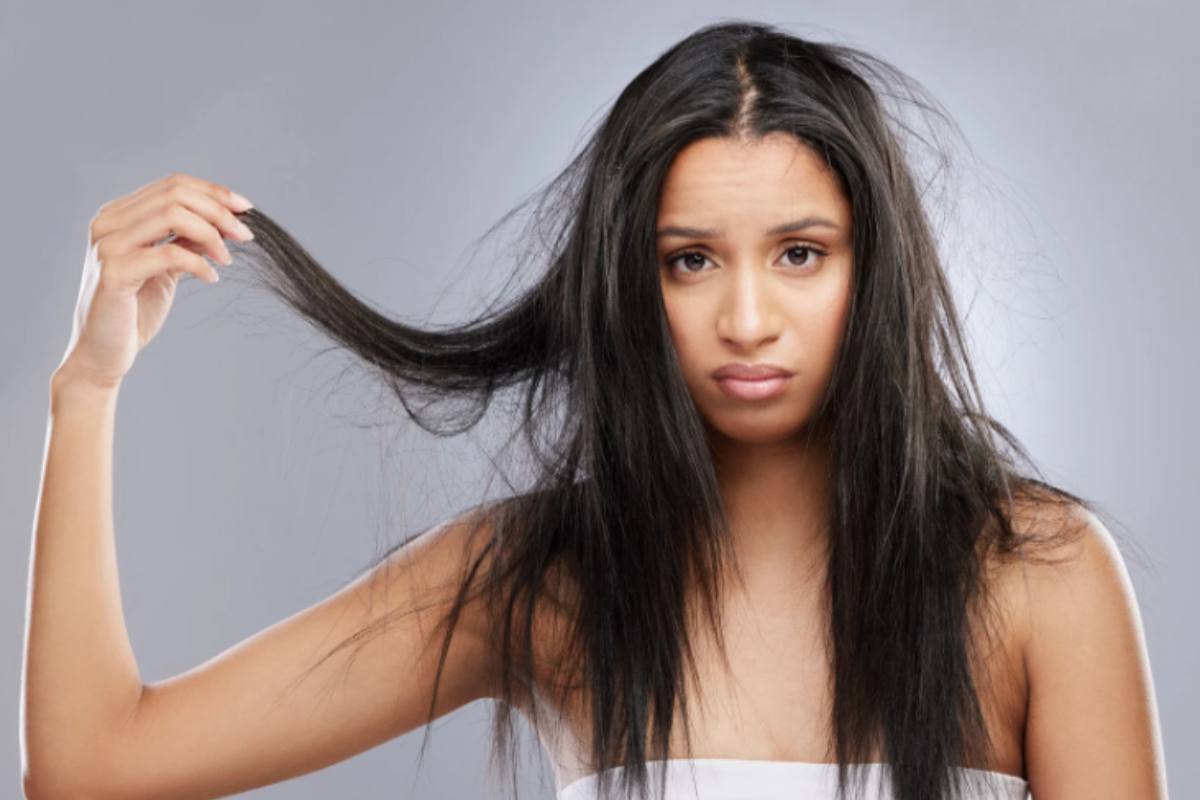 ragazza triste che si tiene una ciocca di capelli