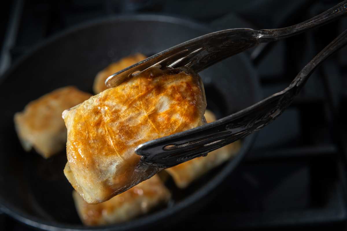 Persona che prende bocconcino pollo fritto con pinze