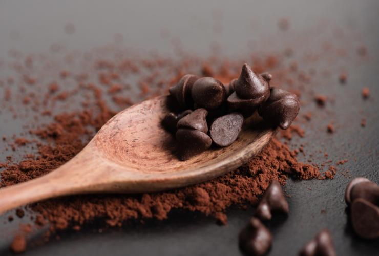gocce di cioccolato sul mestolo di legno e cacao in polvere