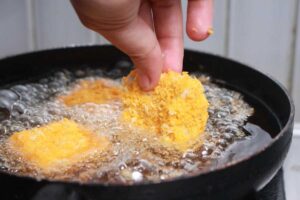 Persona che frigge nuggets in una padella