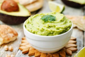 hummus di avocado dentro ad una ciotola con sopra una foglia di menta