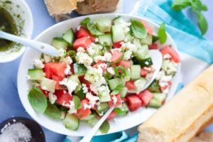 insalata con anguria cetrioli e feta dentro ad un piatto con accanto del pane