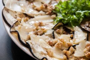 carpaccio di melanzane su un piatto con insalata e noci