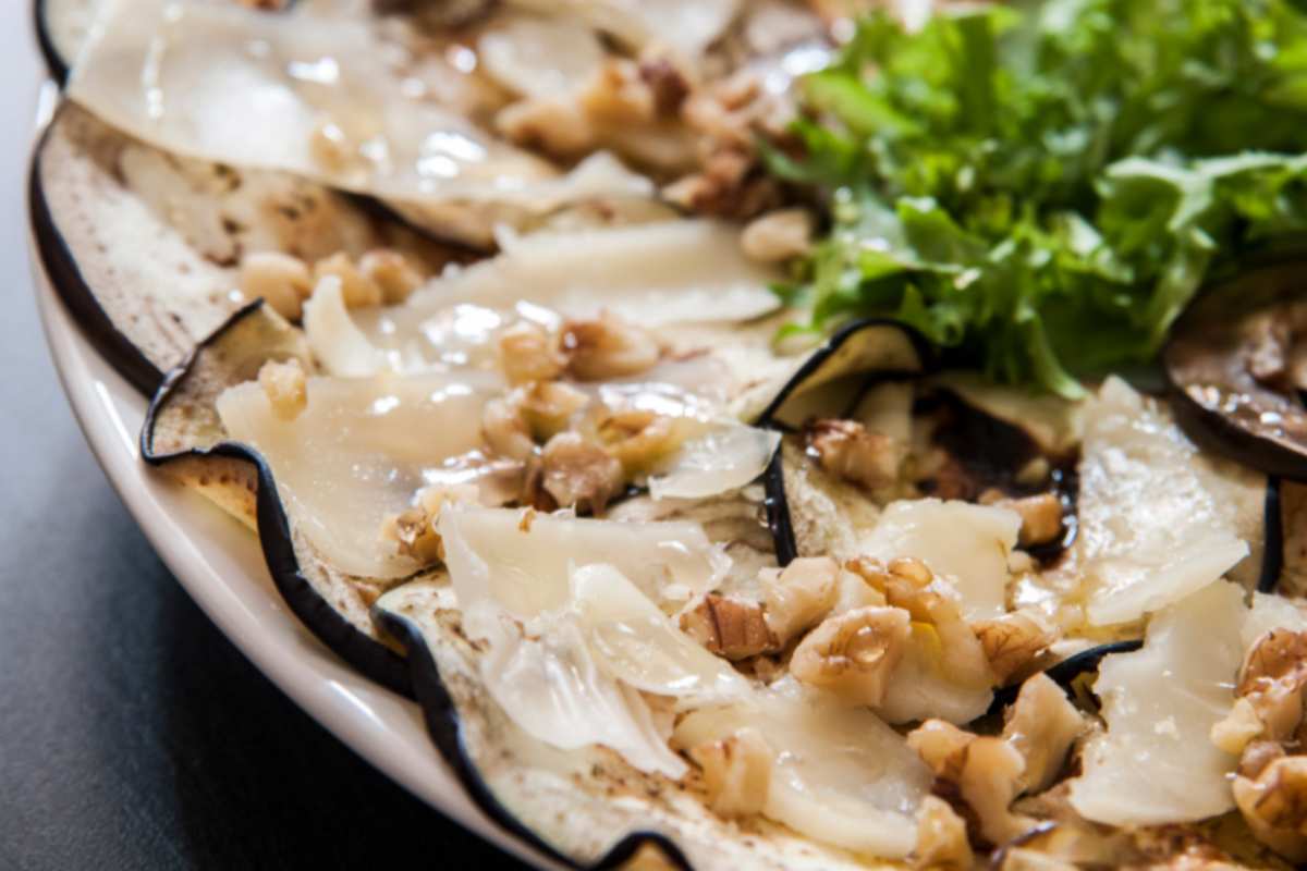 carpaccio di melanzane su un piatto con insalata e noci